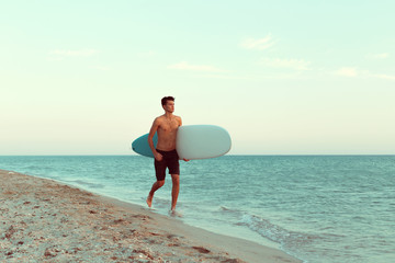 Handsome surfer holding his surfboard