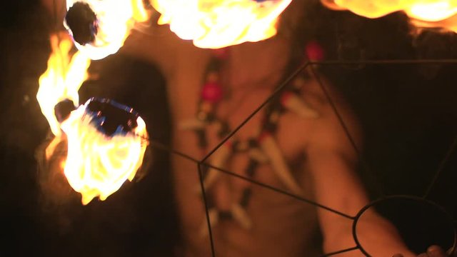 Fire show performance. A handsome man spining fire and beating close to the camera