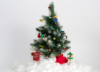 Christmas tree featuring  plastic animals, wooden birds, fake snow and other ornament toys against gray background- eclectic Christmas display concept
