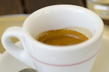 Closeup photo of a cup of espresso coffee standing on a table