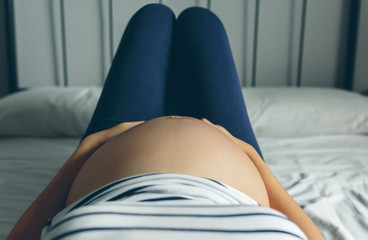 Pregnant woman lying in bed touching her belly