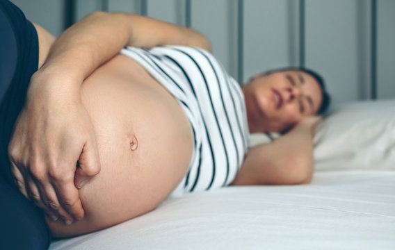 Pregnant woman sleeping and holding her belly