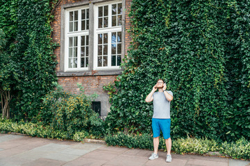 man stands in front of building in ivy and listins music
