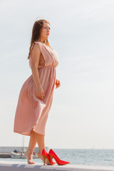 Woman wearing long light pink dress on jetty