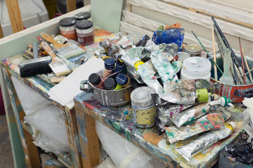 Art studio atelier table full of used artistic oil paint tube brush equipment workshop background