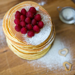 Tasty homemade pancakes with cream and raspberry. On wooden table. Village kitchen