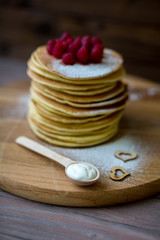 Tasty homemade pancakes with cream and raspberry. On wooden table. Village kitchen