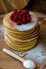 Tasty homemade pancakes with cream and raspberry. On wooden table. Village kitchen