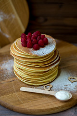 Tasty homemade pancakes with cream and raspberry. On wooden table. Village kitchen