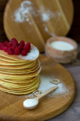 Tasty homemade pancakes with cream and raspberry. On wooden table. Village kitchen