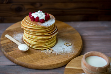 Tasty homemade pancakes with cream and raspberry. On wooden table. Village kitchen