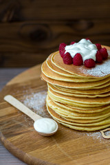 Tasty homemade pancakes with cream and raspberry. On wooden table. Village kitchen
