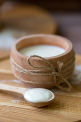 Fototapeta na wymiar Milk in wooden cup. Spoon with homemade cream. Kitchen in the village
