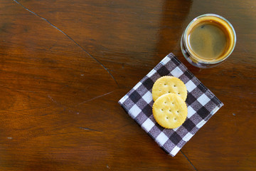 top view of espresso coffee with two pieces of cookies on piece of cloths on the wooden table with copy space for text.