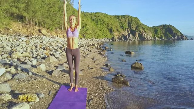 Drone Shows Girl Doing Yoga against Hills on Ocean Coast Sky
