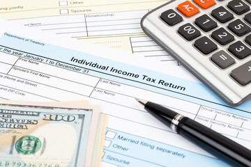 Tax form with calculator, pen, and dollar banknote; document are mock-up