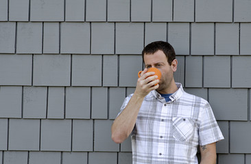 Man drinking from an orange coffee mug.