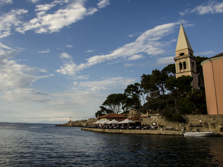 the sea , the clouds and the bell tower, view of a church at the seaside, veli losinj, croatia