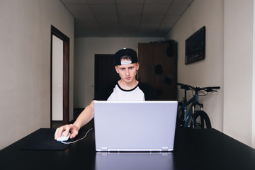 Conceived young man looking at a laptop while working at home.