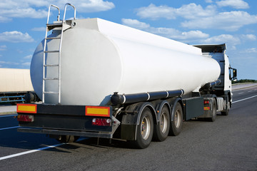 oil truck on road with blank cistern and cloudy sky, cargo transportation concept
