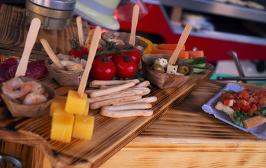 a wooden plank with cheese, tomatos and soup sticks and containers with sauce.