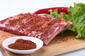 Raw pork ribs with herbs and spices on wooden board. Ready for cooking.