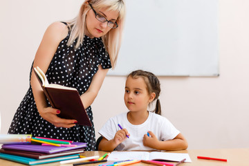 Young preschool teacher teaching little girls in classroom