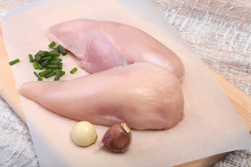 Fototapeta premium Raw chicken breast fillets and garlic ready for cooking on wooden board