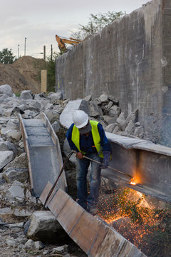building worker, man  of about fifty, wearing a protection helmet and protection vest doing a welding job on a building site 