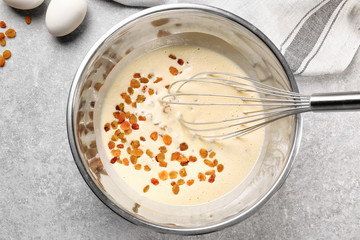 Bowl with raw dough and raisins on kitchen table