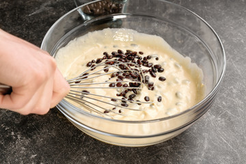 Chef preparing dough with chocolate dragee on kitchen table, closeup