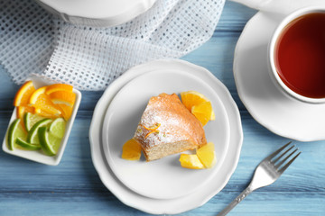 Delicious cake and sliced citrus fruits on wooden table