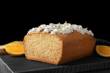 Delicious citrus cake with whipped cream on dark cutting board