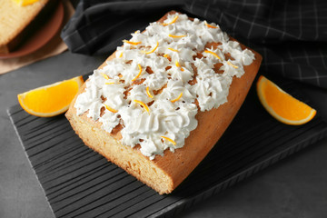 Delicious citrus cake with whipped cream on dark cutting board