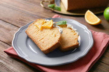 Delicious sliced citrus cake with whipped cream on wooden table
