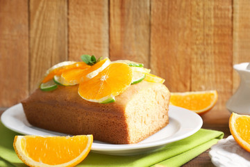 Delicious citrus cake with sliced orange on wooden background