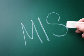 Female hand writing management abbreviation MIS on chalk board