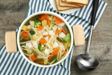 Saucepan with delicious turkey soup on wooden table