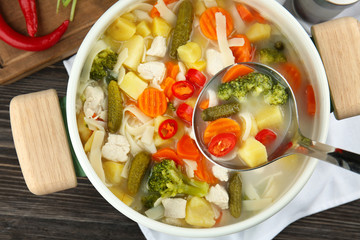 Saucepan with delicious turkey soup on table, top view