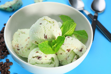 Bowl with delicious mint chocolate chip ice cream on color background, closeup