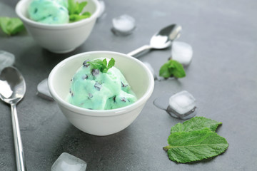 Bowl with delicious mint chocolate chip ice cream on grey table