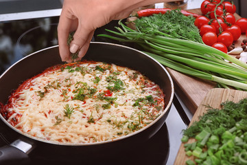 Woman pouring dill on eggs in purgatory