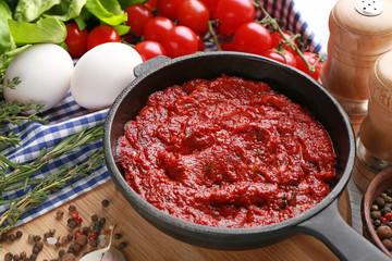 Frying pan with tasty spicy sauce on table