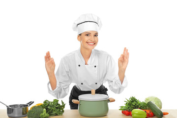 Young female chef near table with different products, on white background