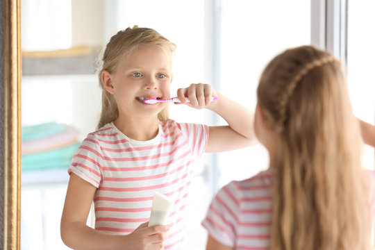 Cute little girl cleaning teeth at home