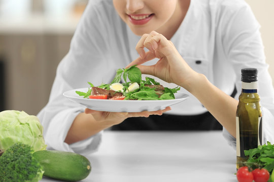Young female chef with tasty dish in kitchen