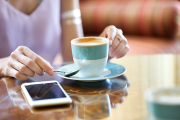 Beautiful young woman drinking coffee in cafe, closeup