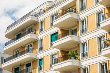 orange facaded building with curved white balconies and brick facade