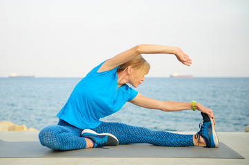 Young athletic woman exercising outdoors: cool down and stretch for flexibility