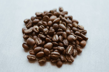 Dark brown natural coffee beans laying on a table. Ingredients for espresso, cappuccino or latte.